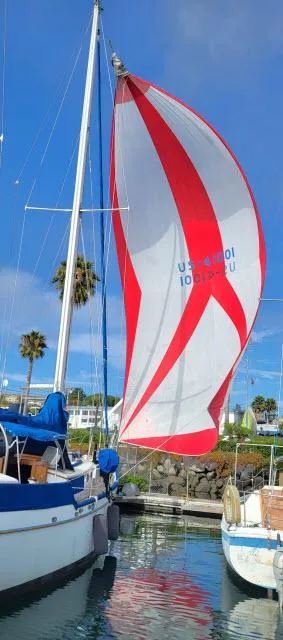 Slide: The Image of 1978 Brewer 45 Ketch sailboat with red and white spinnaker in marina. - 43