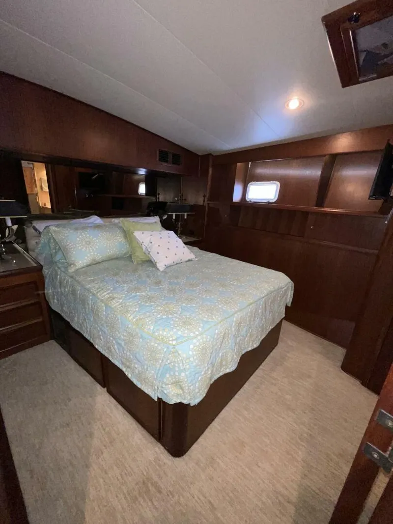 Slide: The Image of 1985 Hatteras Enclosed Bridge bedroom with wood paneling and cozy bedding. - 13