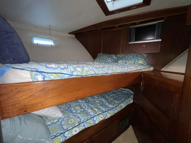 Slide: The Image of Interior of 1985 Hatteras Enclosed Bridge with bunk beds and floral bedding. - 16