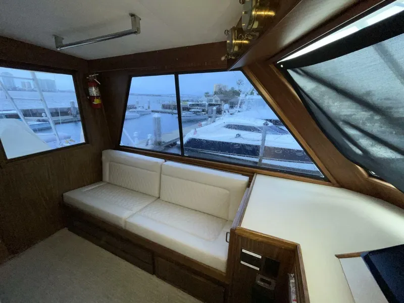 Slide: The Image of Interior of 1985 Hatteras Enclosed Bridge yacht with white seating and marina view. - 27