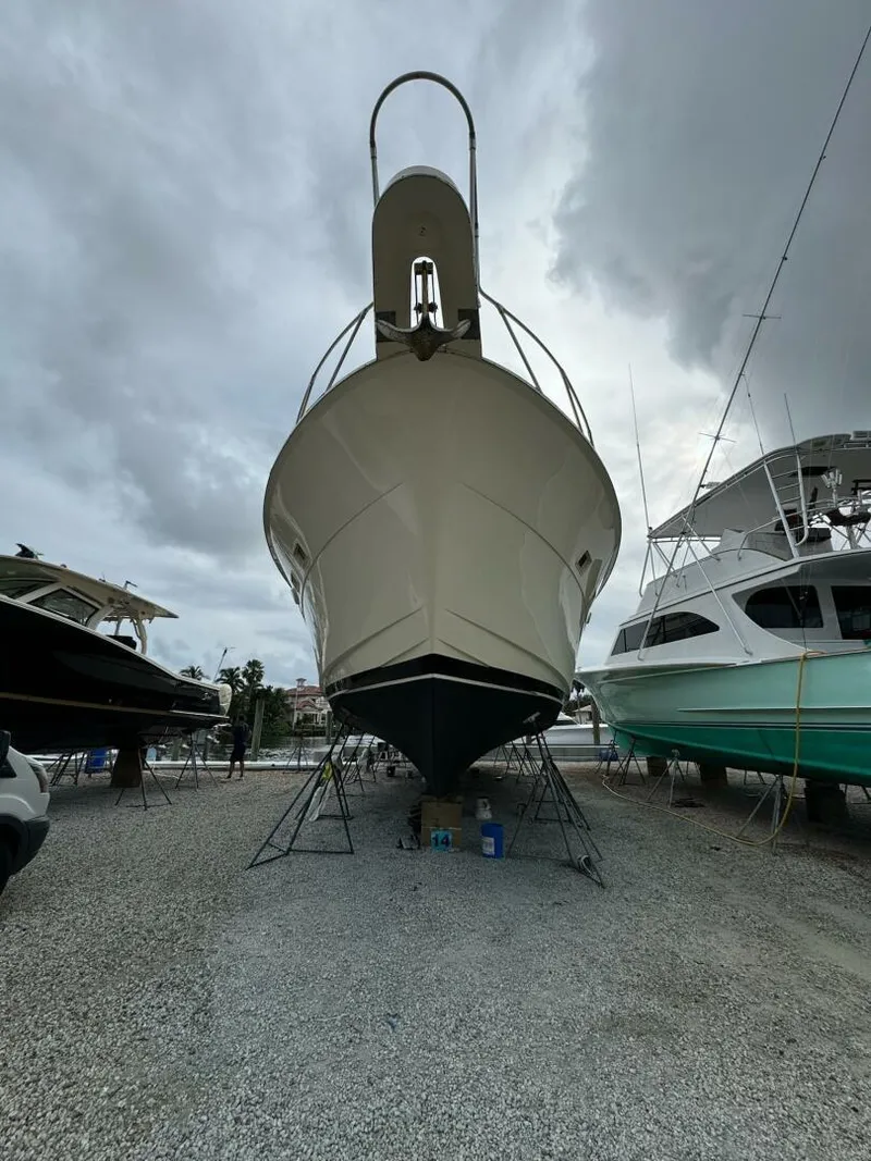 Slide: The Image of 1985 Hatteras Enclosed Bridge yacht on dry dock under cloudy skies. - 34
