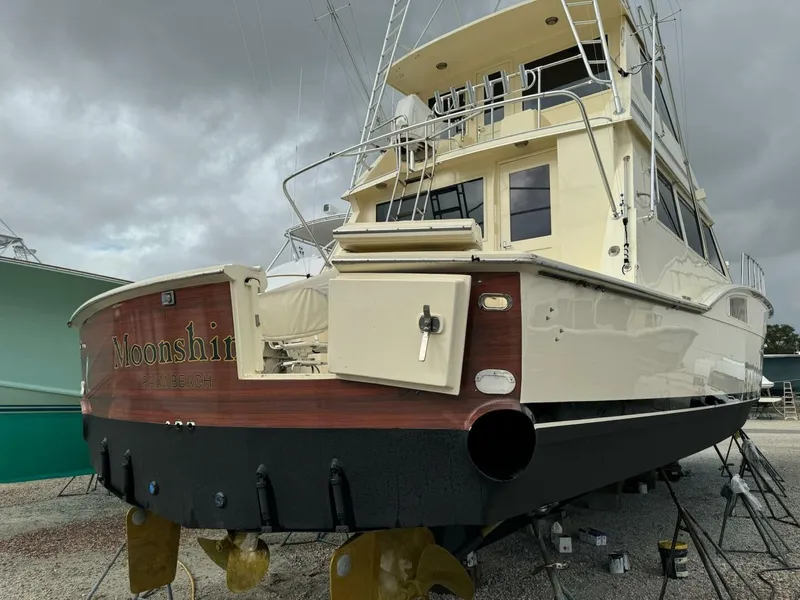 Slide: The Image of 1985 Hatteras Enclosed Bridge yacht on land, showcasing stern and enclosed upper deck. - 36