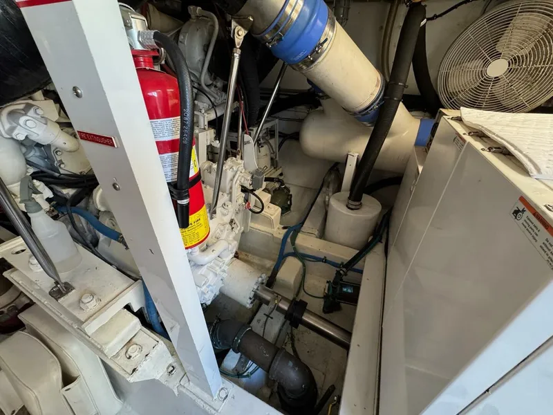 Slide: The Image of Engine room of a 1985 Hatteras Enclosed Bridge yacht, featuring mechanical components and a fire extinguisher. - 44