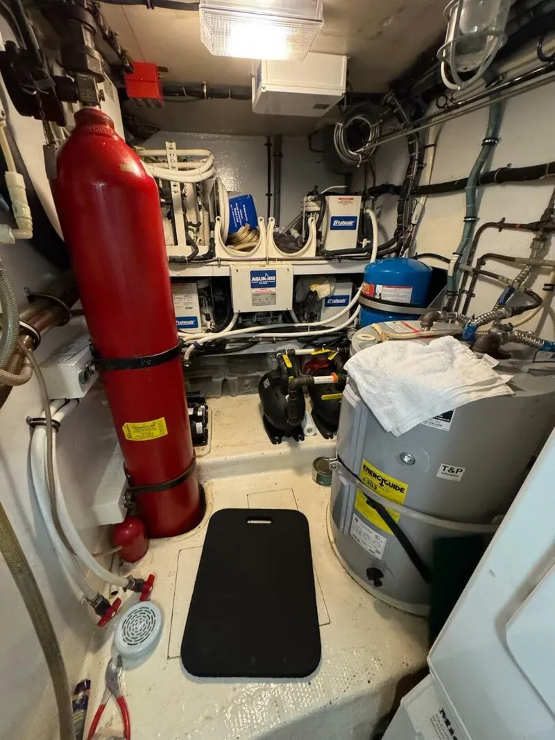 Slide: The Image of Engine room of a 1985 Hatteras Enclosed Bridge yacht, featuring equipment and piping. - 46