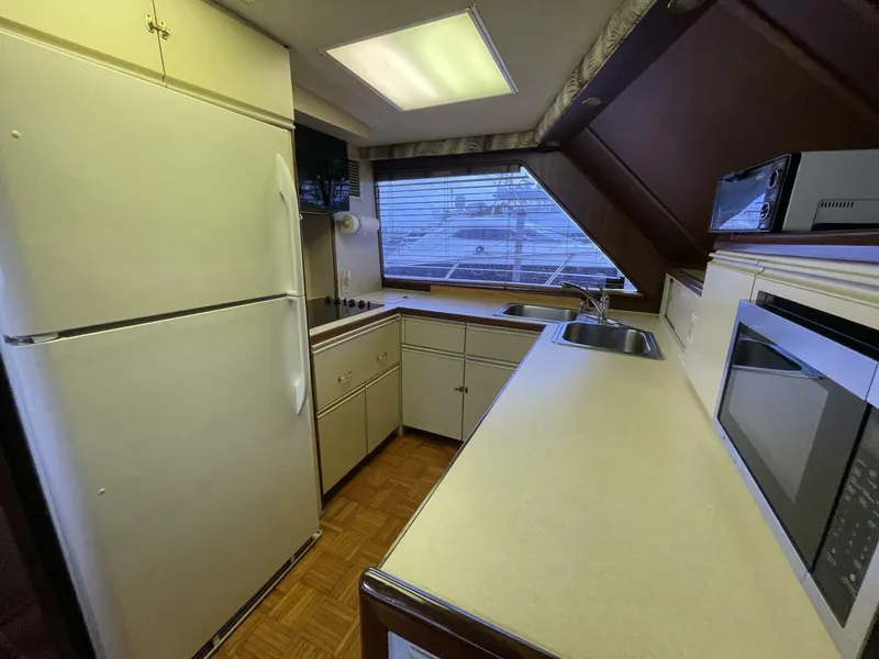 Slide: The Image of 1985 Hatteras Enclosed Bridge yacht kitchen with appliances, large window, and ample counter space. - 9