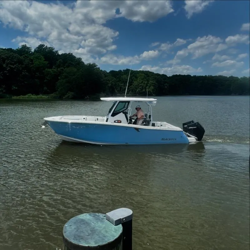 Slide: The Image of 2024 Blackfin 272 boat cruising on a calm lake under a partly cloudy sky. - 1