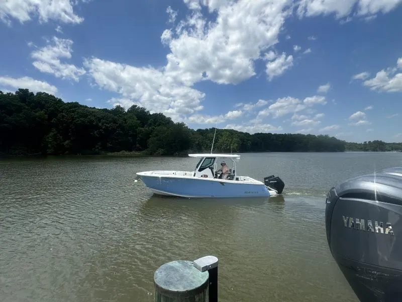 Slide: The Image of 2024 Blackfin 272 boat cruising on a scenic lake under a partly cloudy sky. - 2