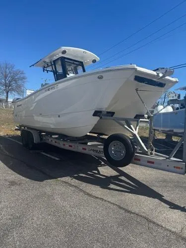 Slide: The Image of 2023 World Cat 260 CC-X boat on trailer, parked outdoors under clear blue sky. - 2