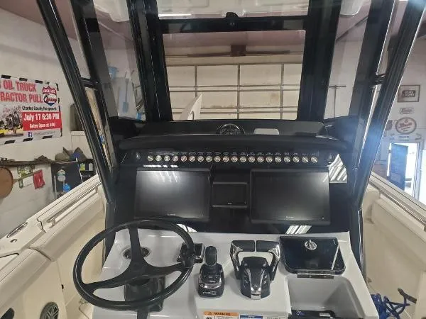 Slide: The Image of 2023 World Cat 260 CC-X boat dashboard with dual screens and steering wheel in a garage setting. - 9