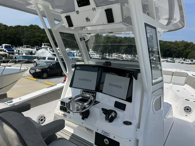 Slide: The Image of 2024 Sea Fox 328 Commander boat dashboard with Garmin displays at a marina. - 8