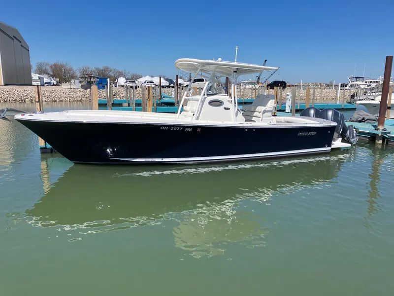 Slide: The Image of 2013 Regulator 28 boat docked in marina, clear sky, calm water. - 0