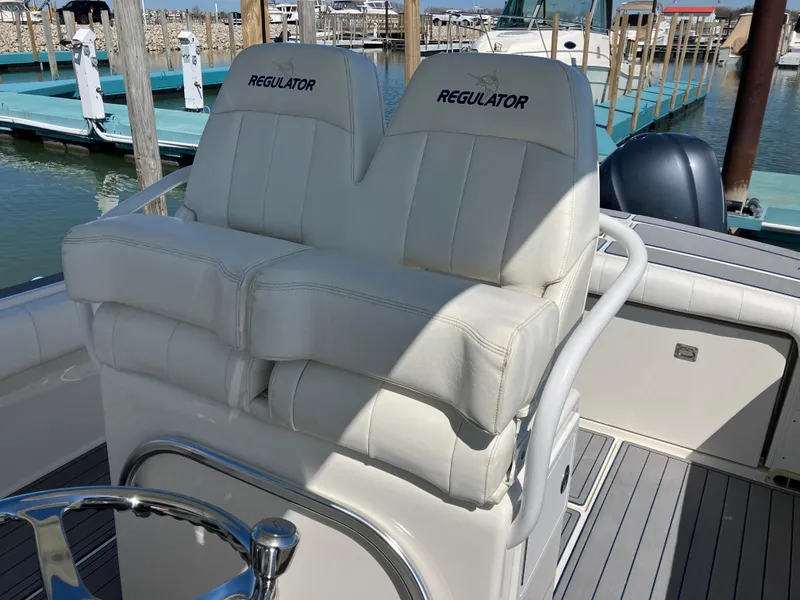 Slide: The Image of 2013 Regulator 28 boat with dual white cushioned seats at the helm. - 30
