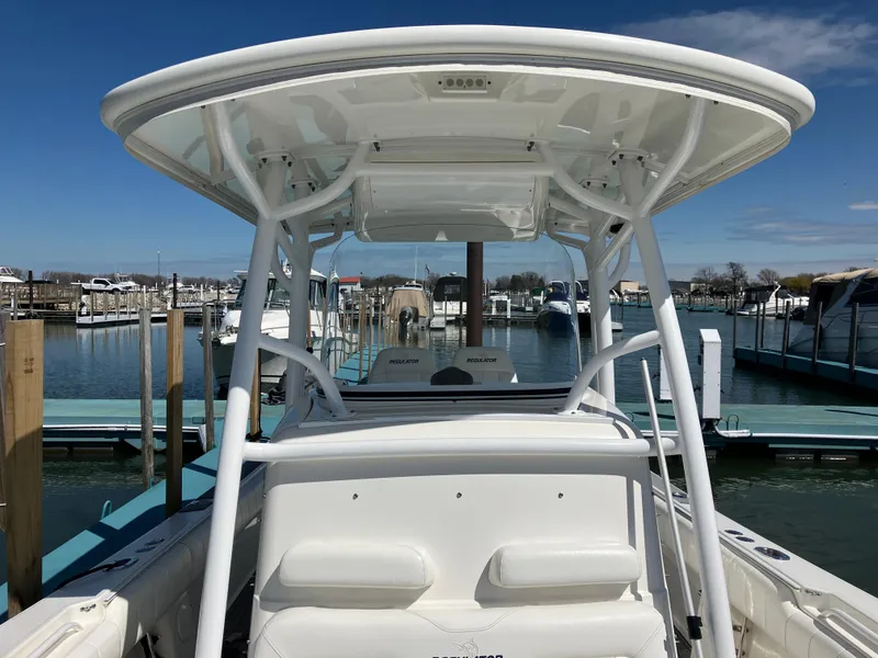 Slide: The Image of 2013 Regulator 28 boat with T-top, docked in a marina under clear skies. - 32