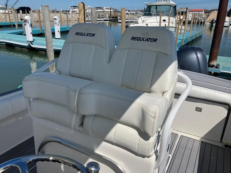 Slide: The Image of 2013 Regulator 28 boat with dual cushioned seats at a marina. - 33