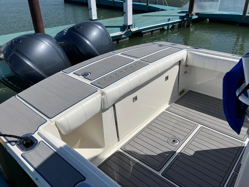 Slide: The Image of 2013 Regulator 28 boat with dual engines, docked, featuring spacious deck and seating area. - 4