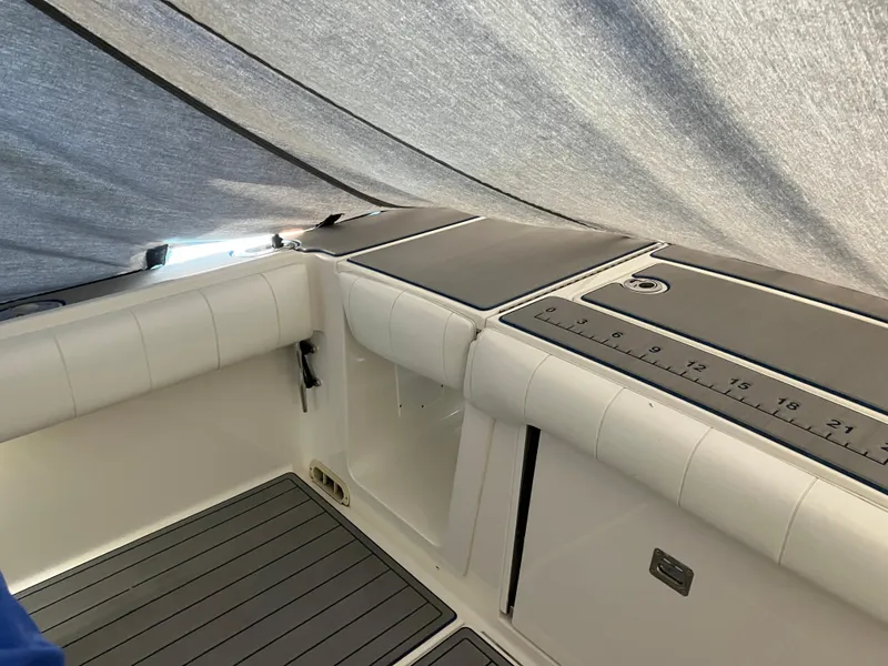 Slide: The Image of 2013 Regulator 28 boat interior under cover, featuring cushioned seating and measurement markings. - 5