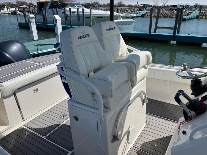 Slide: The Image of 2013 Regulator 28 boat with white seating at a marina dock. - 8
