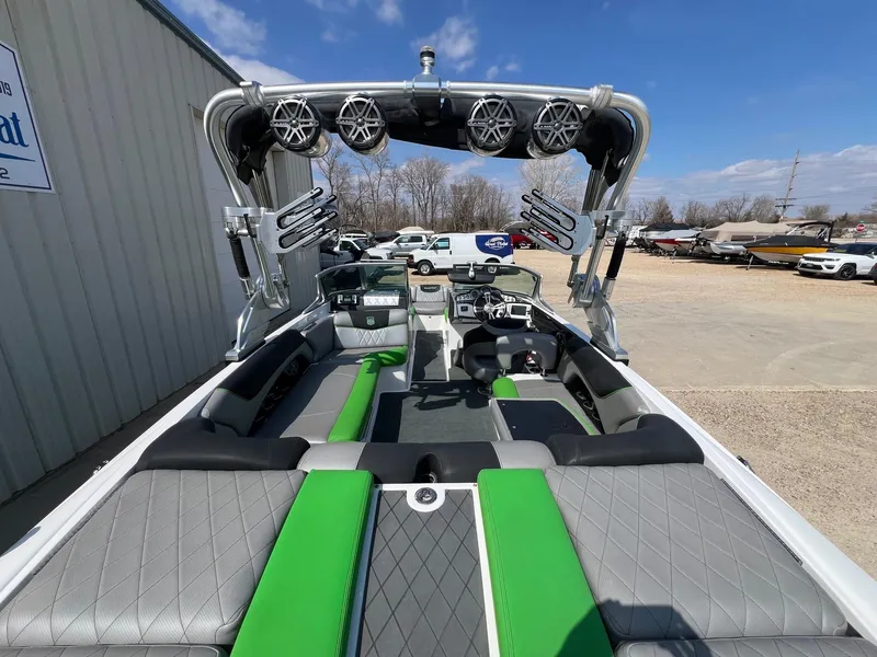 Slide: The Image of 2013 MasterCraft X-25 boat interior with green and gray seating, tower speakers, and wakeboard racks. - 12