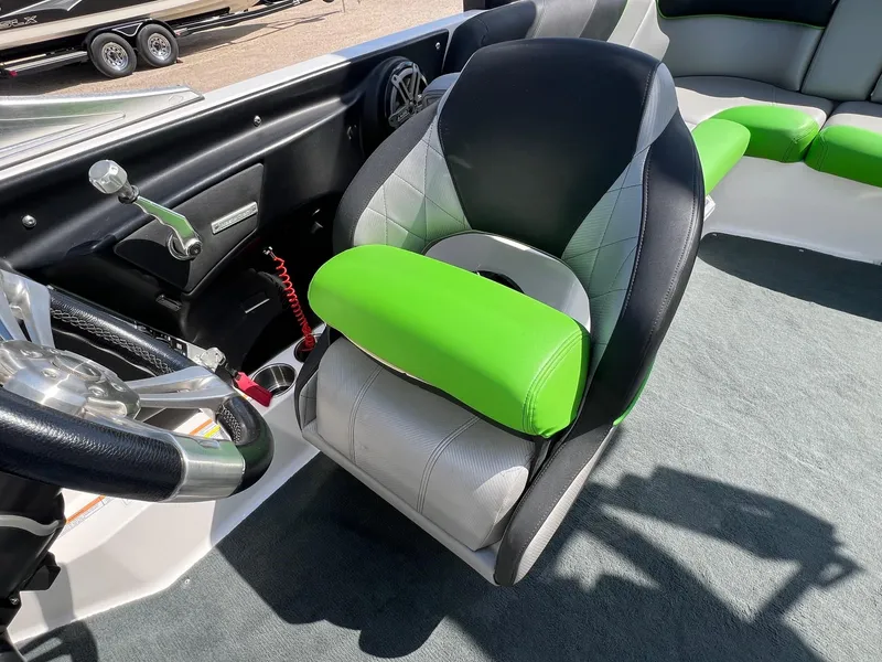 Slide: The Image of 2013 MasterCraft X-25 boat interior with green and gray seating, steering wheel, and controls. - 24