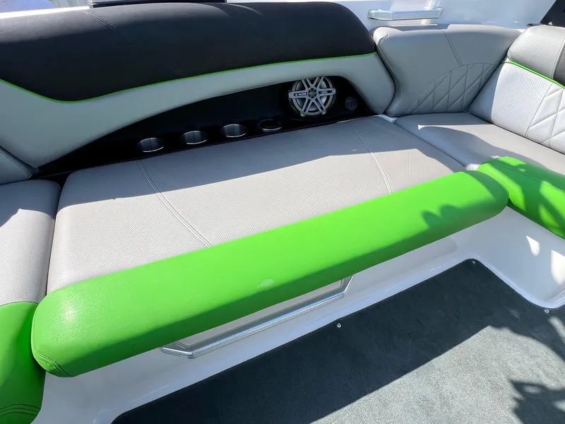 Slide: The Image of 2013 MasterCraft X-25 boat interior with green and gray seating, featuring cup holders and speaker. - 33