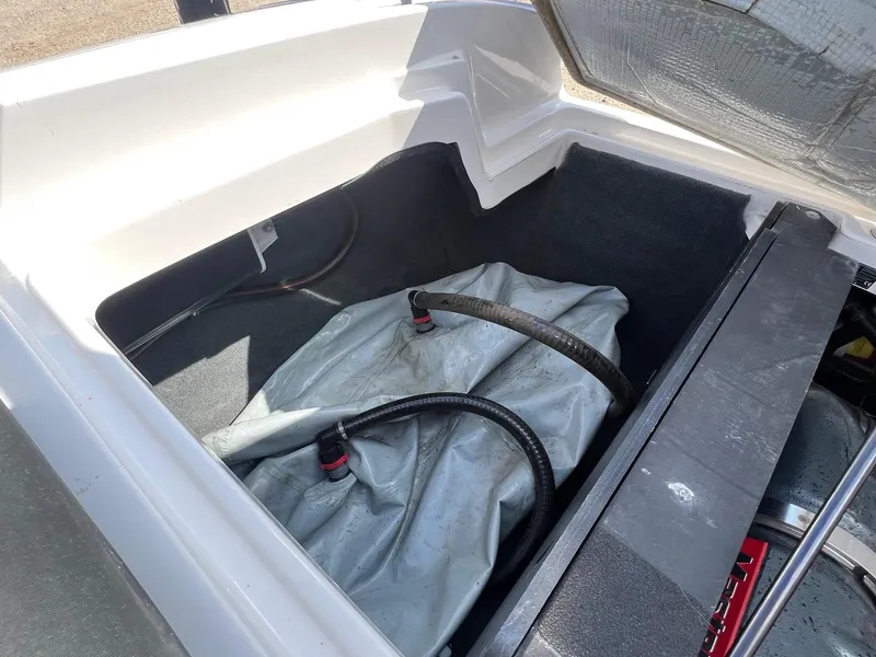 Slide: The Image of Open storage compartment in a 2013 MasterCraft X-25 boat, showing ballast bag and hoses. - 40