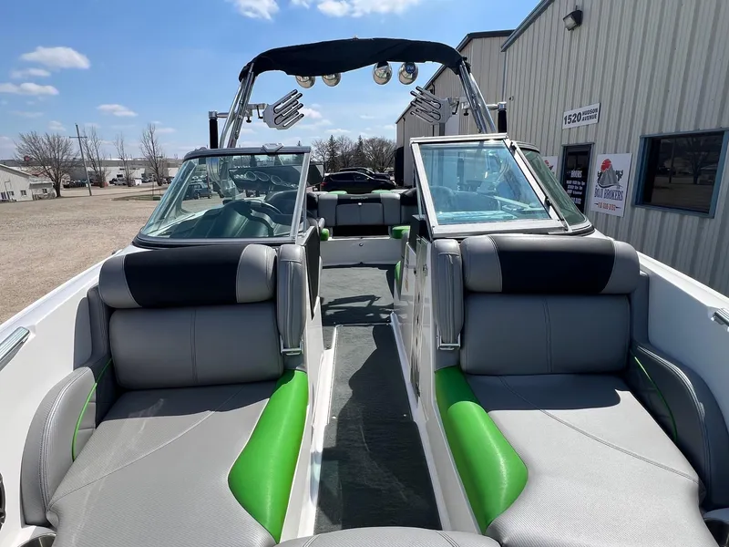Slide: The Image of 2013 MasterCraft X-25 boat interior with green and gray seating, parked outdoors. - 6