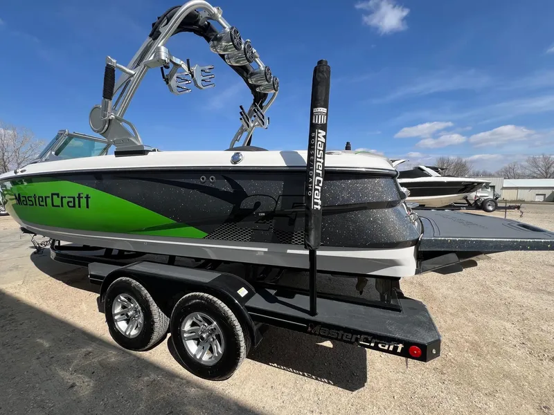 Slide: The Image of 2013 MasterCraft X-25 boat with green and black design on a trailer. - 7