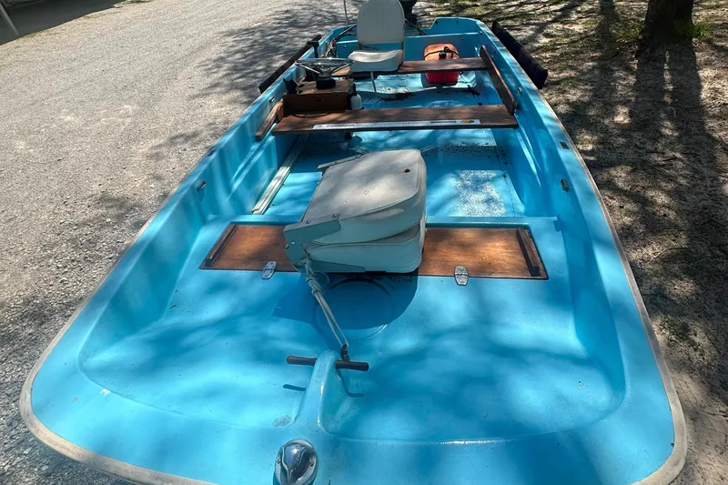 Slide: The Image of 1967 Boston Whaler 13 boat with blue interior and wooden accents, parked on gravel. - 10