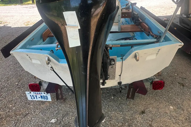 Slide: The Image of 1967 Boston Whaler 13 boat with outboard motor, rear view, parked on gravel. - 11