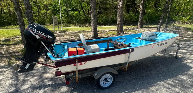 Slide: The Image of 1967 Boston Whaler 13 boat with Mercury outboard motor on a trailer, parked outdoors. - 2