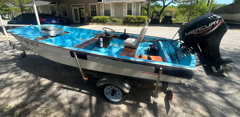 Slide: The Image of 1967 Boston Whaler 13 boat with Mercury outboard motor on a trailer, parked outdoors. - 3