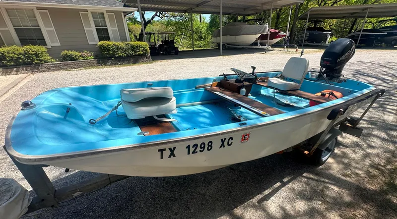 Slide: The Image of 1967 Boston Whaler 13 boat with blue interior, parked on a trailer in a driveway. - 4