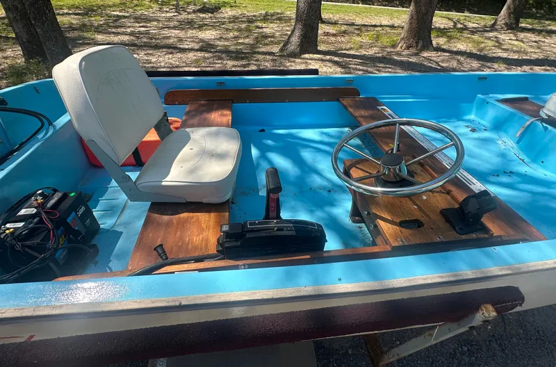 Slide: The Image of 1967 Boston Whaler 13 boat interior with steering wheel and seating, featuring blue and wood accents. - 6