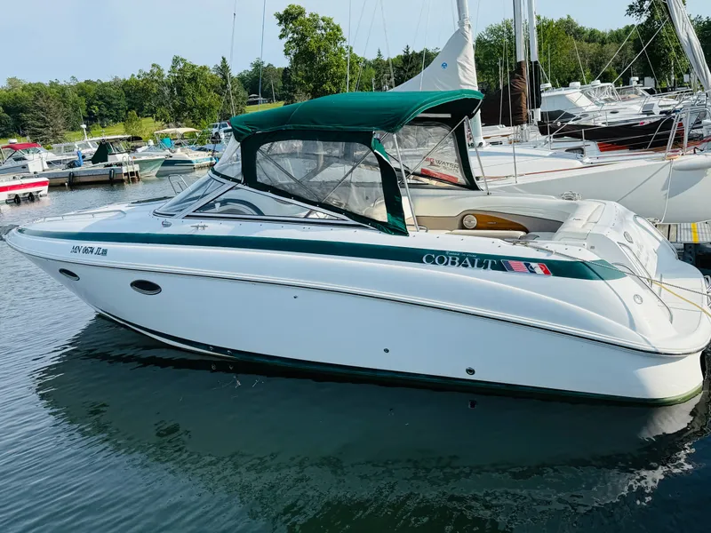 The Image of 2000 Cobalt 293 boat docked in marina, featuring green canopy and sleek white design. - 0