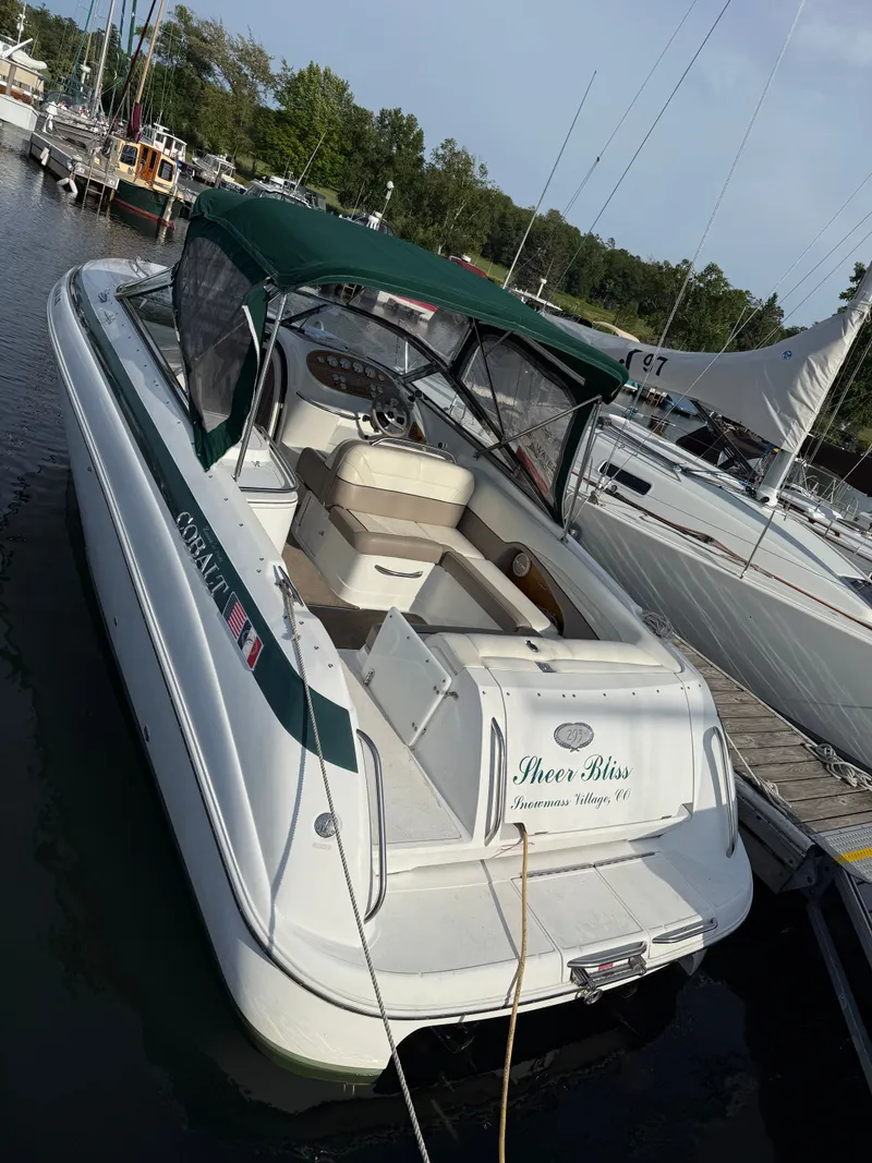 Slide: The Image of 2000 Cobalt 293 boat docked, green canopy, white hull, serene marina setting. - 10