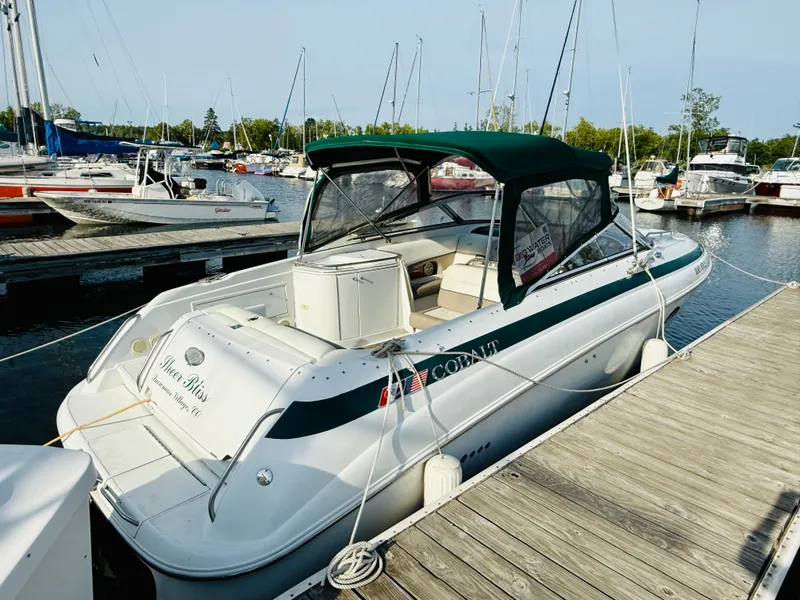 Slide: The Image of 2000 Cobalt 293 boat docked at marina, featuring green canopy and white interior. - 13