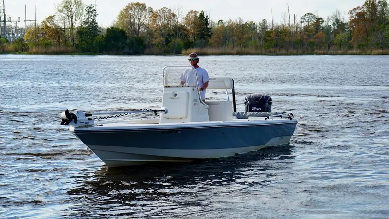 Slide: The Image of 2011 Pathfinder 2300 HPS boat on calm water, with a person at the helm. - 5