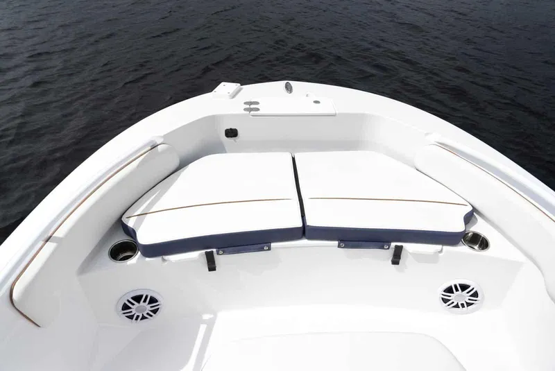 Slide: The Image of 2025 Stingray 173 CC boat interior with cushioned seating and cup holders on calm water. - 12