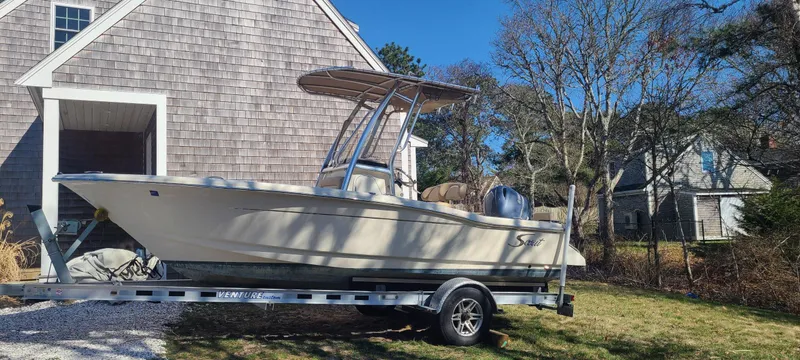 Slide: The Image of 2021 Scout 195 Sportfish boat on trailer beside a house, under clear blue sky. - 8