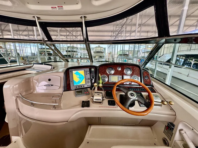Slide: The Image of 2004 Sea Ray 420 Sundancer helm with navigation controls and wooden steering wheel. - 13