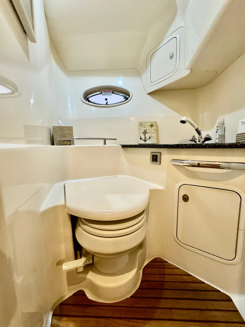 Slide: The Image of 2004 Sea Ray 420 Sundancer bathroom with toilet, sink, and wooden floor. - 25