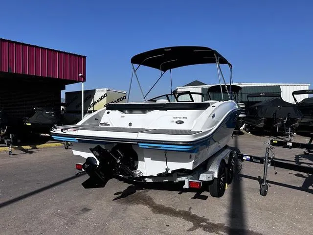 Slide: The Image of 2023 Sea Ray SPX 210 boat on trailer, parked outdoors under clear blue sky. - 4