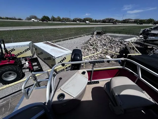 Slide: The Image of 2014 Sun Tracker Bass Buggy 18 DLX pontoon boat parked near trailers and tractors. - 9