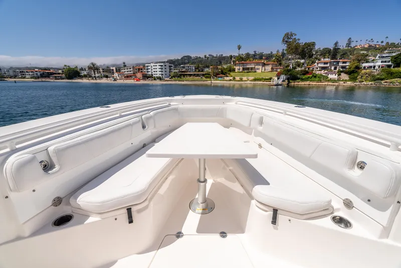Slide: The Image of 2015 Everglades 325 Center Console boat with white seating and table, docked near waterfront homes. - 15