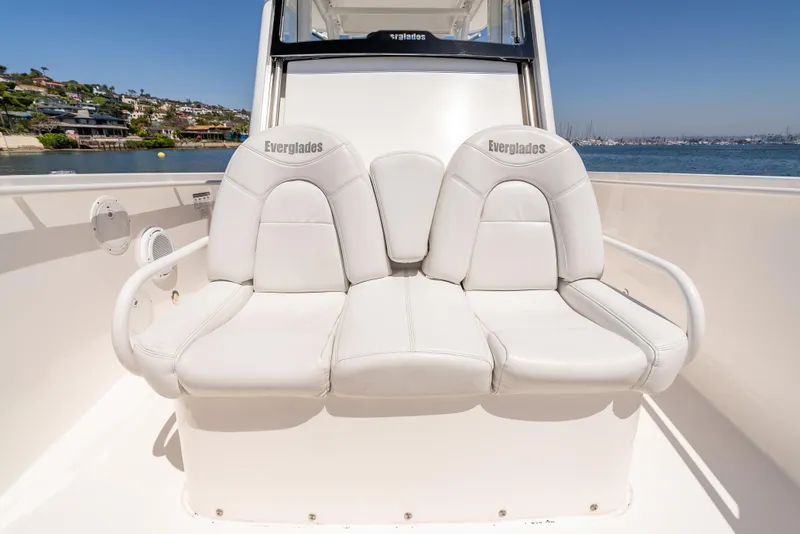 Slide: The Image of 2015 Everglades 325 Center Console boat with white cushioned seating, docked by the water. - 17