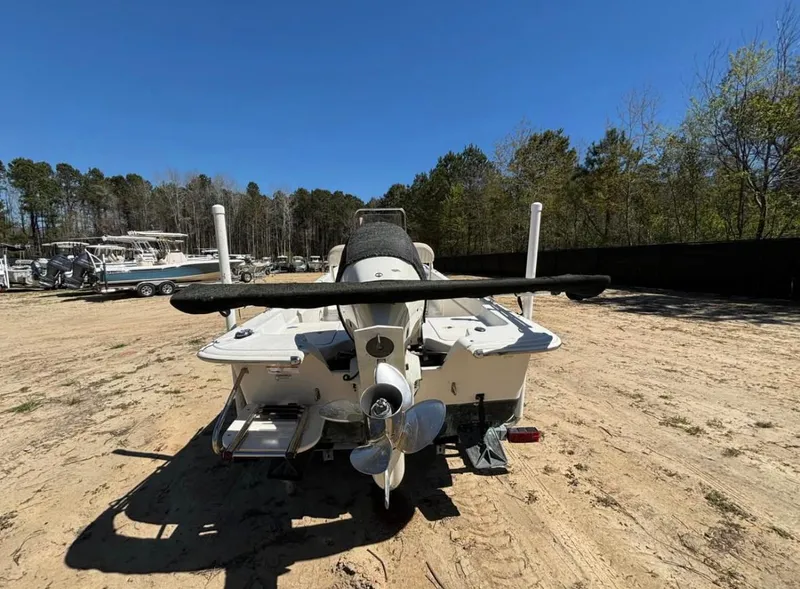 Slide: The Image of 2017 Carolina Skiff 18 JVX CC boat, rear view, parked on sandy ground, surrounded by trees. - 3