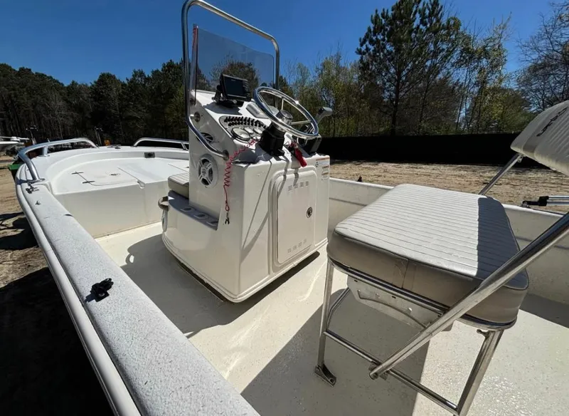 Slide: The Image of 2017 Carolina Skiff 18 JVX CC boat interior with console and seating, surrounded by trees. - 4