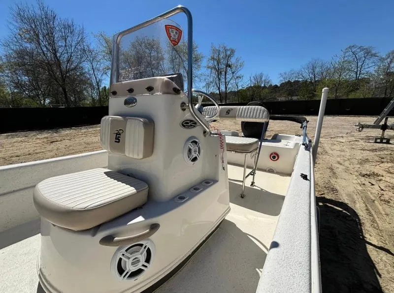 Slide: The Image of 2017 Carolina Skiff 18 JVX CC boat with beige seating, parked on sandy ground. - 5