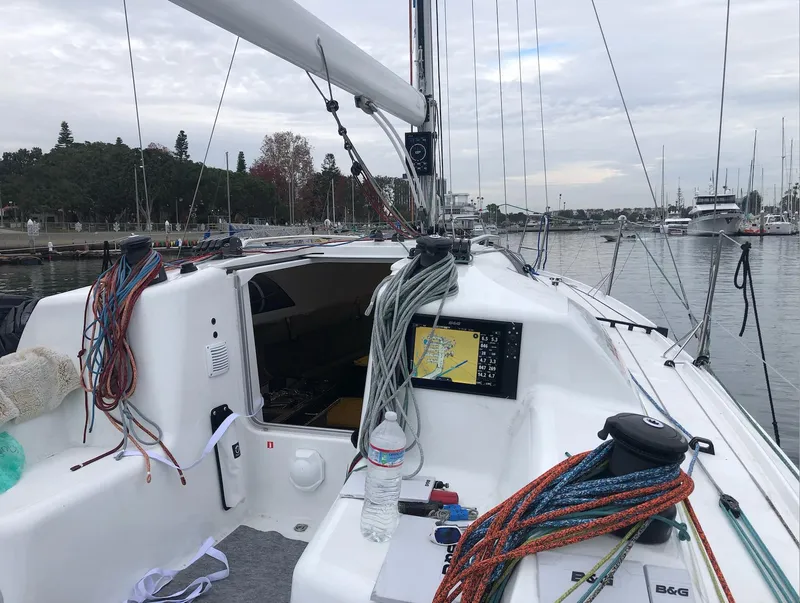Slide: The Image of 2021 Jeanneau SUNFAST 3300 sailboat cockpit with ropes and navigation equipment in a marina. - 12