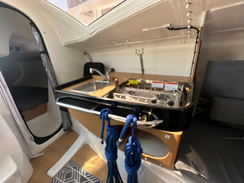 Slide: The Image of Interior of 2021 Jeanneau Sun Fast 3300 sailboat, featuring compact kitchen area with sink and stove. - 20